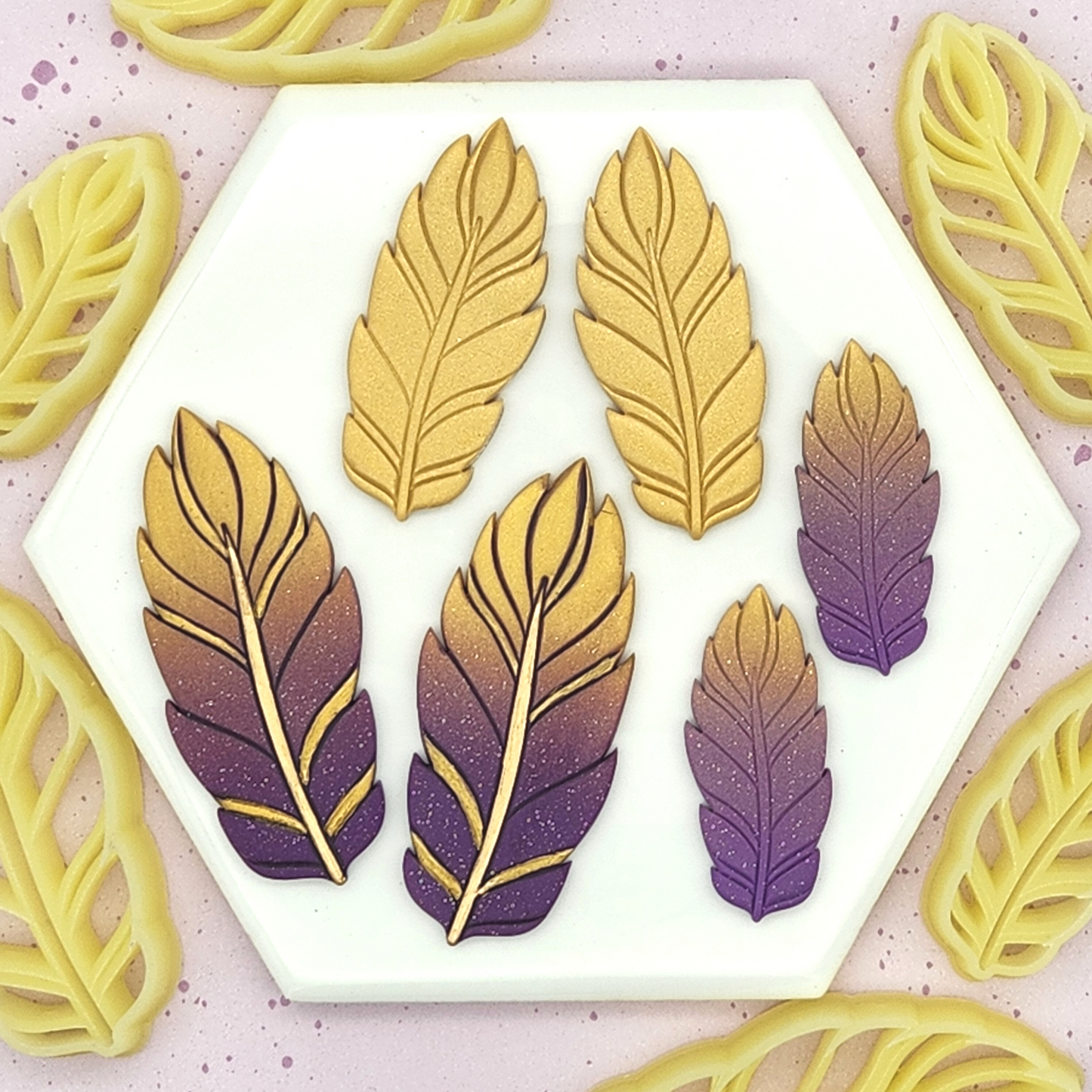 finished earrings alongside the cutters on a hexagonal white tile, surrounded by additional feather cutters