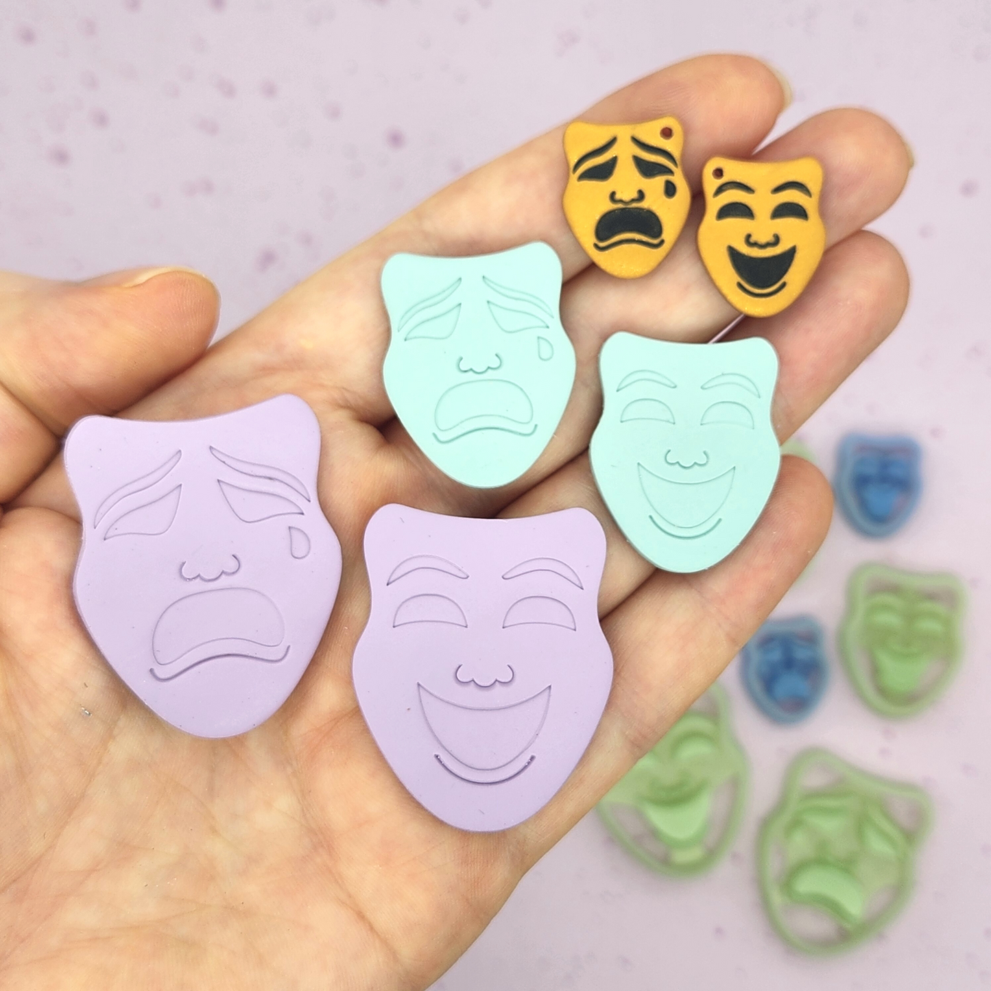 image shows a hand holding several finished clay pieces in different colors and sizes