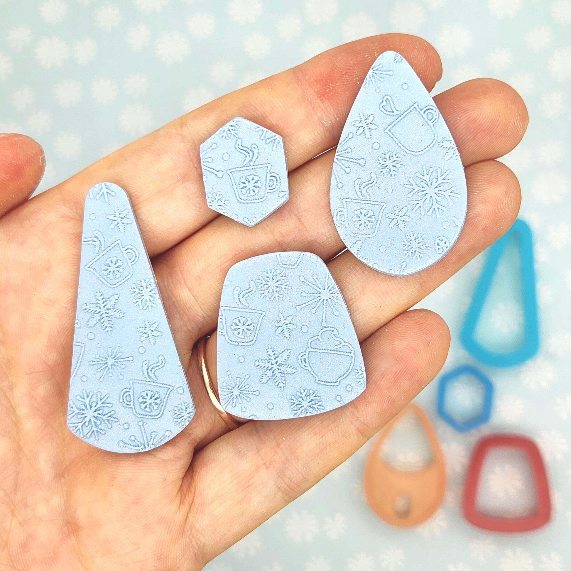 Hand holding Cold Weather Cocoa texture imprinted on polymer clay shapes