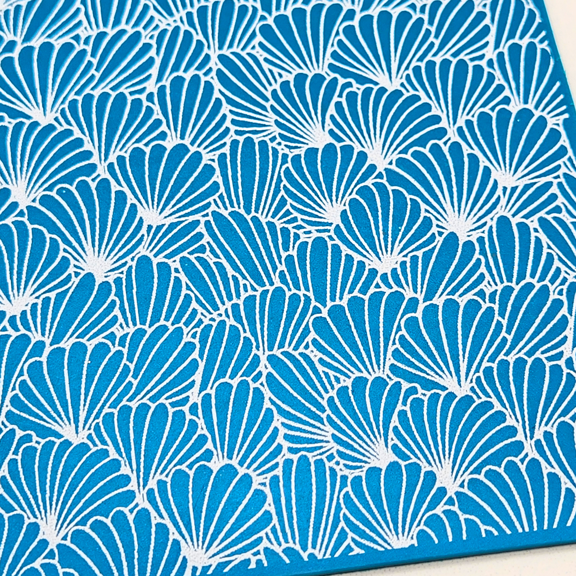 Detailed view of abstract shell pattern on blue polymer clay slab.