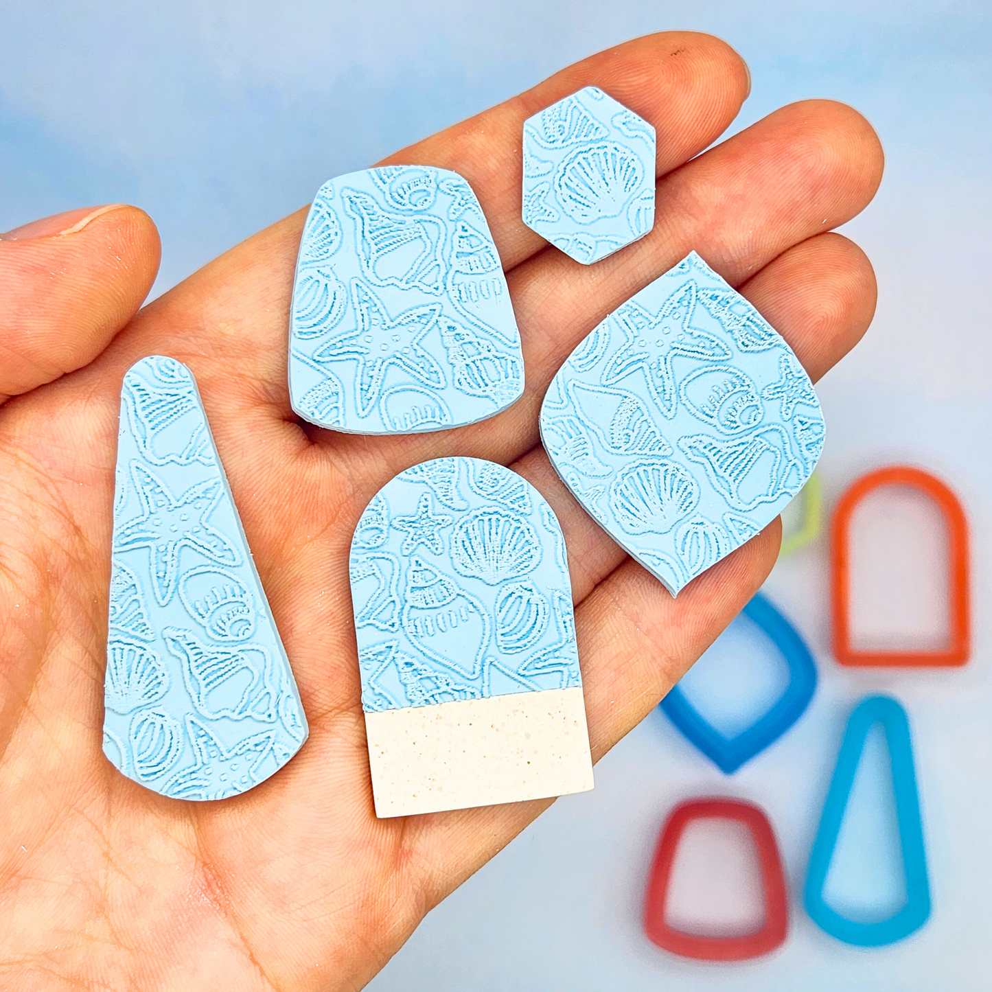 Cut-out pieces from the sea-themed texture sheet, displayed in hand to show various shapes and how the patterns look when used on polymer clay.