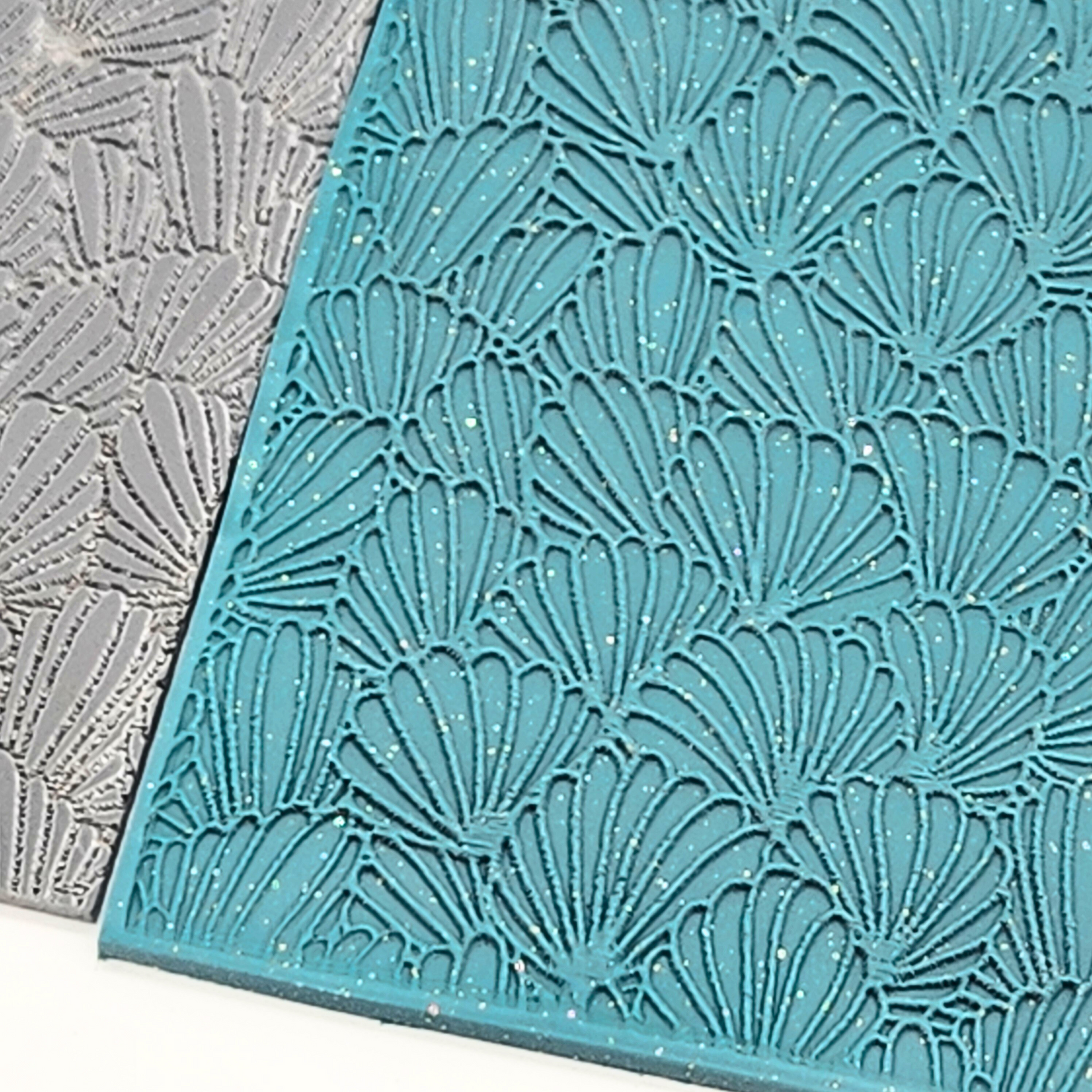 Detailed view of embossed abstract shell pattern on teal polymer clay slab.