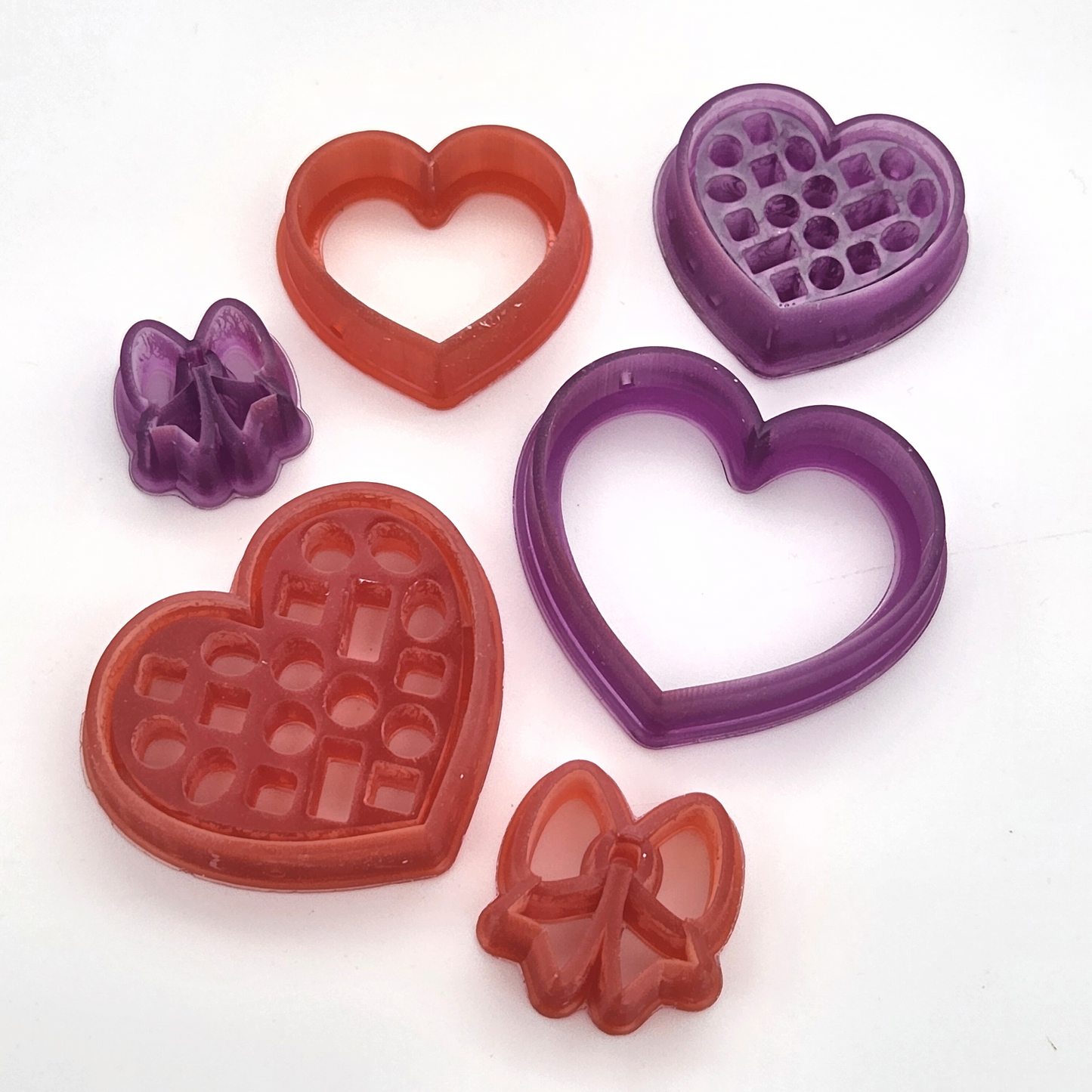 3D Printed Resin box of chocolates clay cutter set including three cutters, a heart-shaped box of chocolates, a lid for the box, and a bow for the lid. Zoomed n close up angle to show sharp edge details
