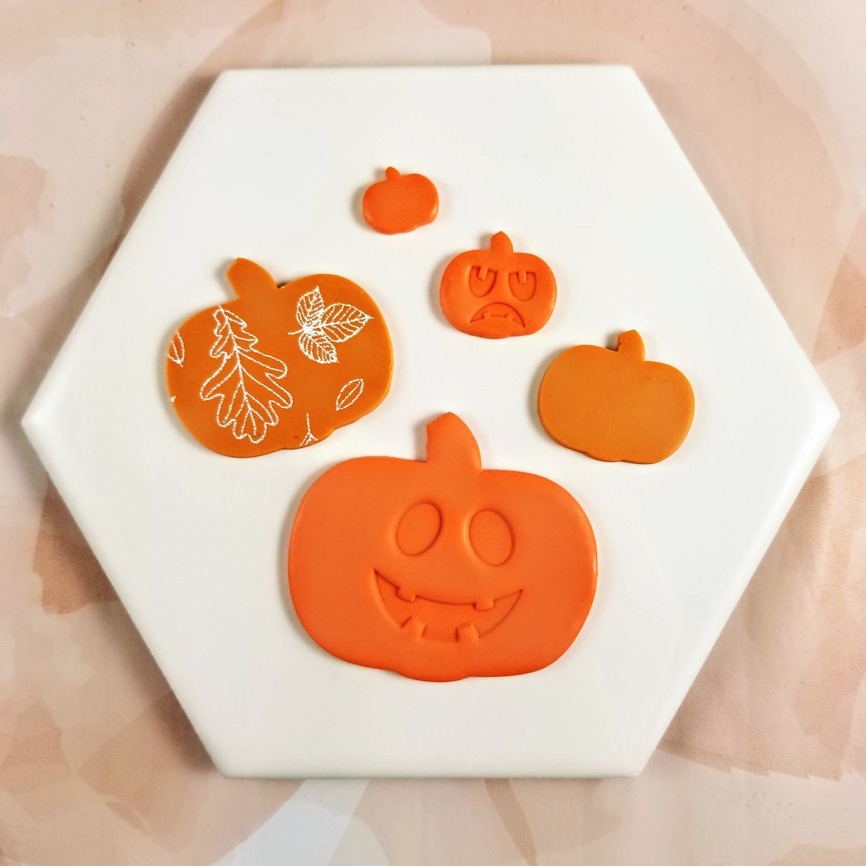 pumpkin shape on polymer clay with jack o lantern faces design and fall leaves silk screen pattern